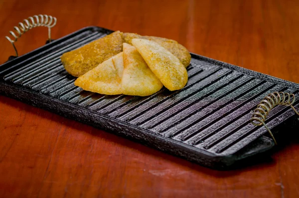 Five empanadas lying in fan formation on black metal grill tablet — Stock Photo, Image