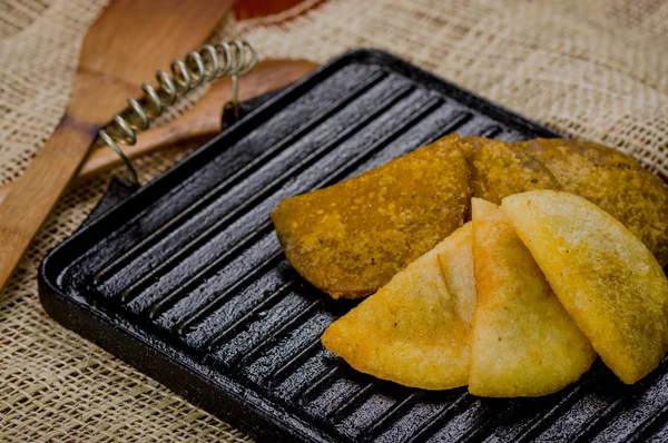 Closeup five empanadas lying in fan formation on black metal grill tablet — Stock Photo, Image