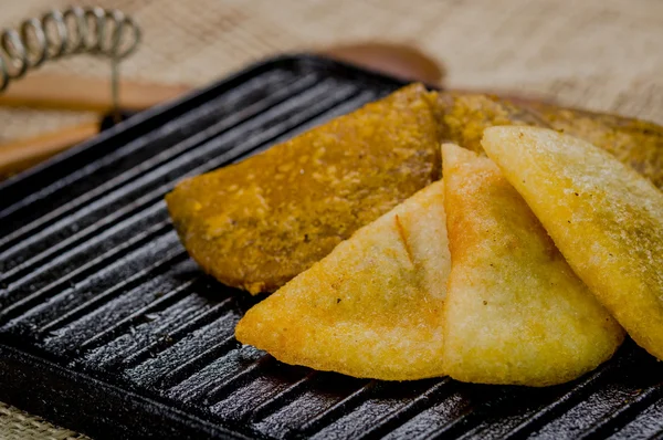 Closeup five empanadas lying in fan formation on black metal grill tablet — Stock Photo, Image