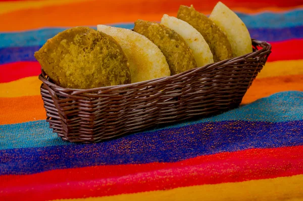 Basket with six empanadas neatly placed inside sitting on latin colorful table cloth — Stock Photo, Image