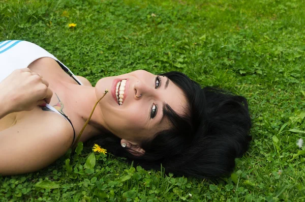 Brunette headshot gros plan horisontal couché sur l'herbe avec regarder à la caméra souriant — Photo