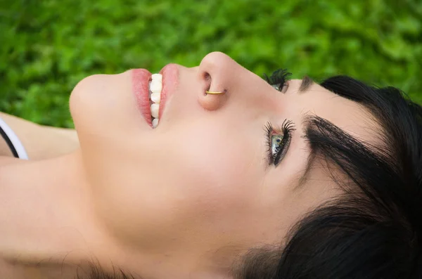 Brunette headshot closeup horisontal lying on grass looking upwards resting — Stock Photo, Image