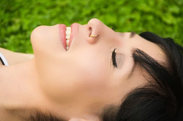 Brunette headshot closeup horisontal lying on grass with eyes closed — Stock Photo, Image