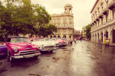 HAVANA, CUBA - DECEMBER 2, 2013: Old classic American cars rides in front of the Capitol. Before a new law issued on October 2011, cubans could only trade cars that were on the road before 1959. clipart