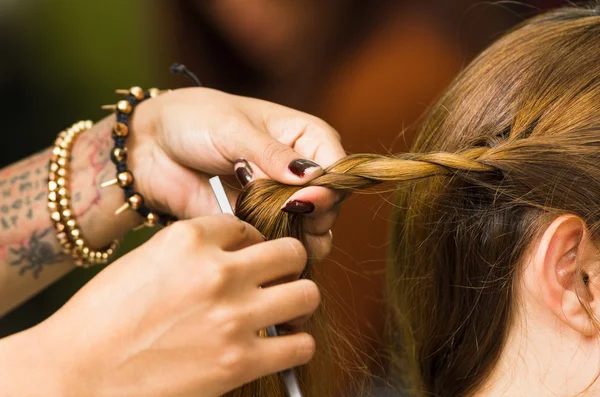 Primo piano mani stilista che lavorano con i capelli castani facendo una torsione — Foto Stock