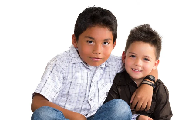 Due piccoli ragazzi ispanici seduti uno accanto all'altro abbracciati come amici, sfondo bianco — Foto Stock