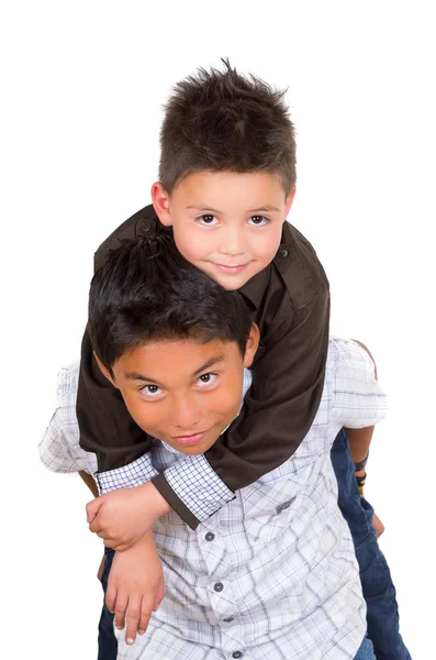 Two small hispanic boys playing, one carrying the other on his back, facing camera — Stock Photo, Image