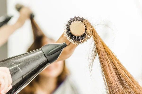 Primo piano spazzola per capelli con capelli bruna roteato intorno e asciugacapelli nero soffiaggio — Foto Stock