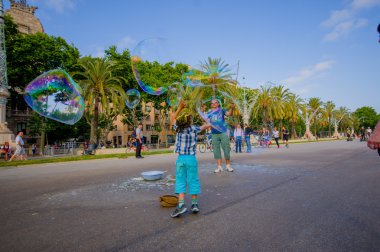 Beautiful wide avenue sorrounded by tall green palm trees and tourists enjoying a nice Barcelona sunny day