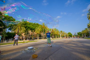 Beautiful wide avenue sorrounded by tall green palm trees and tourists enjoying a nice Barcelona sunny day