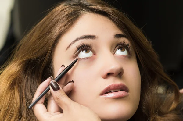 Nahaufnahme Headshot Brünette bekommt Make-up-Behandlung durch professionelle Stylistin Anwendung Eyeliner — Stockfoto