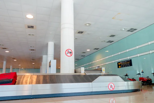 BARCELONA, ESPAÑA - 8 DE AGOSTO DE 2015: Cinta transportadora para equipaje de llegada en el interior de una gran sala de color brillante en el aeropuerto — Foto de Stock