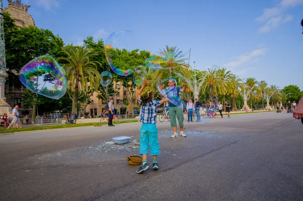 Beautiful wide avenue sorrounded by tall green palm trees and tourists enjoying a nice Barcelona sunny day