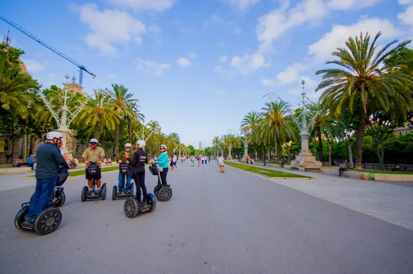 Hermosa avenida amplia rodeada de altas palmeras verdes y turistas disfrutando de un bonito día soleado en Barcelona en segways — Foto de Stock