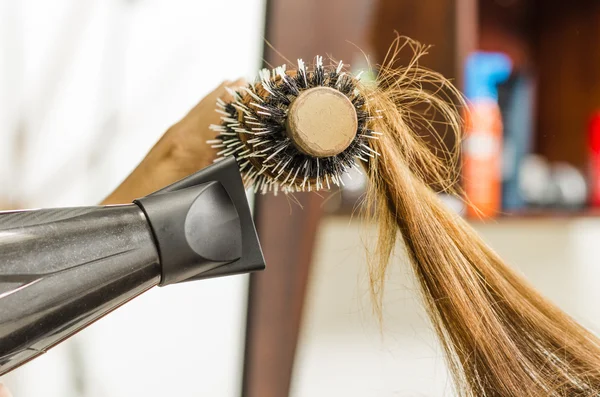 Closeup hairbrush with brunette hair swirled around and black hairdyer blowing — Φωτογραφία Αρχείου