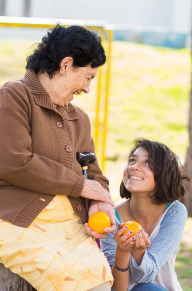 Grandmother granddaughter quality time outdoors holding an orange — Stock Photo, Image