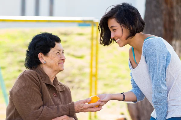 Grandmother granddaughter quality time outdoors holding an orange — Stock Photo, Image