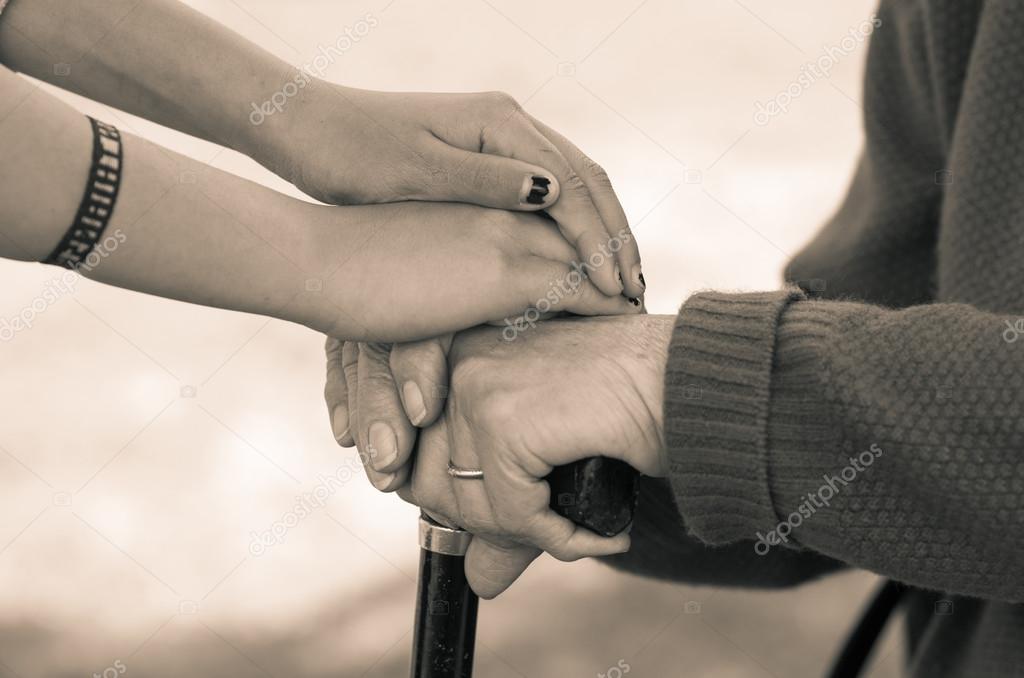 Closeup grandmother granddaughter holding hands, outdoors environment black and white edition