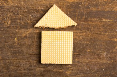 Simple house design illustrated by using rectangular and a triangular cookie on wooden surface