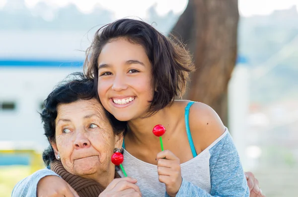 Abuela y nieta posando felices juntas sosteniendo piruletas sonriendo —  Fotos de Stock