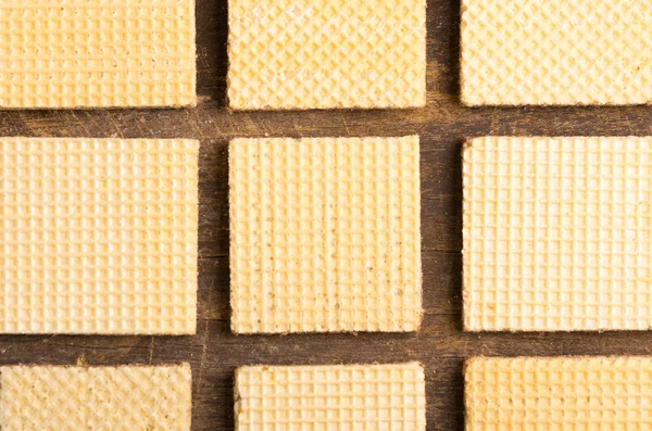 Closeup biscoitos quadrados alinhados na superfície de madeira criando um padrão artístico — Fotografia de Stock