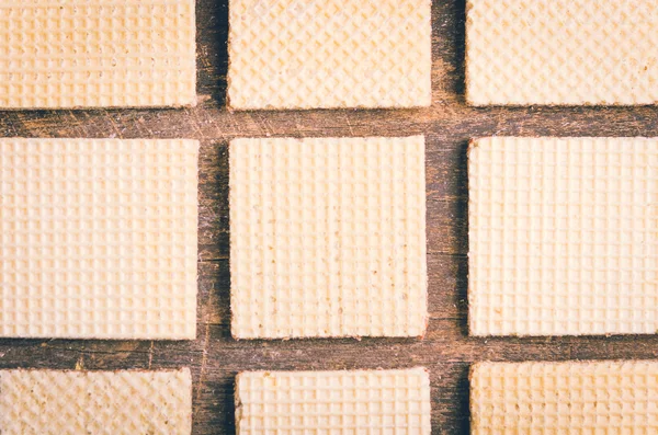 Closeup biscoitos quadrados alinhados na superfície de madeira criando um padrão artístico — Fotografia de Stock