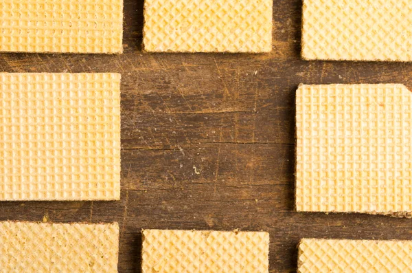 Closeup square cookies lined up on wooden surface crating an artistic pattern, middle snack is missing — Stock fotografie