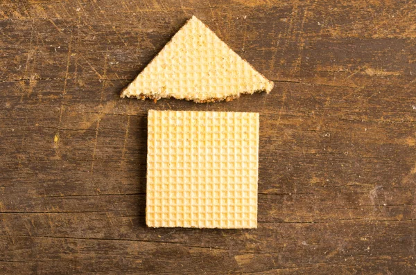 Design semplice della casa illustrato utilizzando un biscotto rettangolare e un biscotto triangolare sulla superficie di legno — Foto Stock