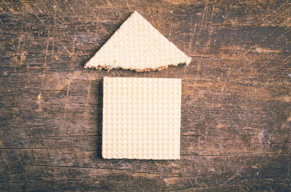 Simple house design illustrated by using rectangular and a triangular cookie on wooden surface — Zdjęcie stockowe