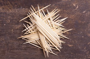 Many toothpicks tightly piled together facing different directions on dark wooden surface