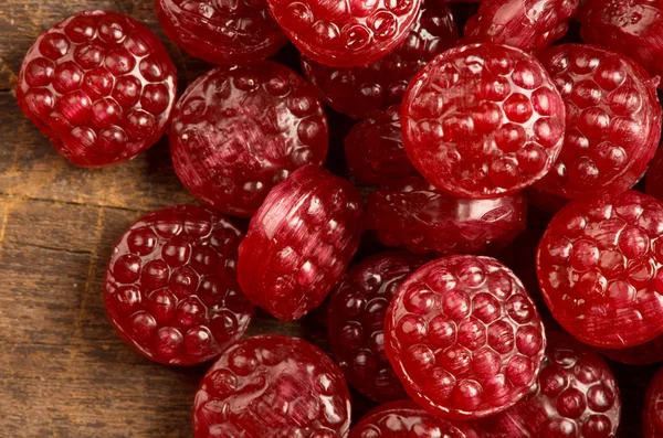 Pile of tasty delicious raspberry hard candy lying on wooden surface — Φωτογραφία Αρχείου