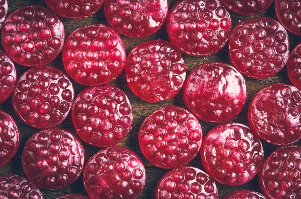 Pile of tasty delicious raspberry hard candy lying on wooden surface — Zdjęcie stockowe