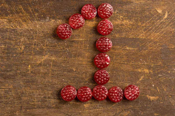 The number one shaped by raspberry hard candy on wooden surface — Zdjęcie stockowe