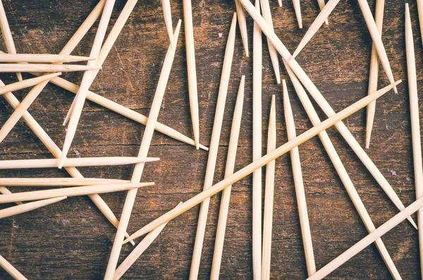 Many toothpicks lying in pile facing different directions on a dark wooden surface — Stock Photo, Image