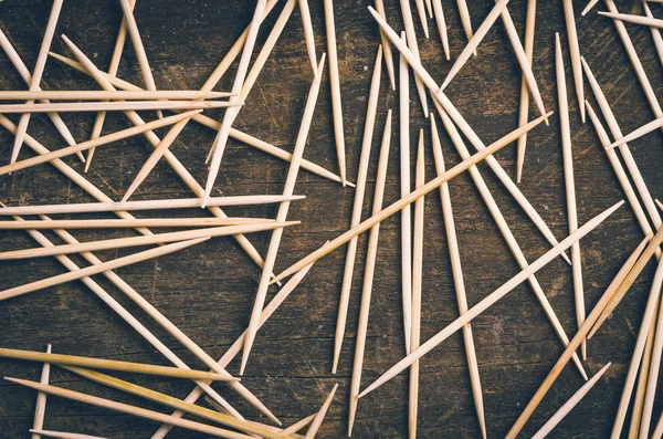 Many toothpicks lying in pile facing different directions on a dark wooden surface — Stockfoto