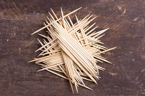 Many toothpicks tightly piled together facing different directions on dark wooden surface — Stock Image Many toothpicks tightly piled together facing different directions on dark wooden surface Royalty Free Stock Images
