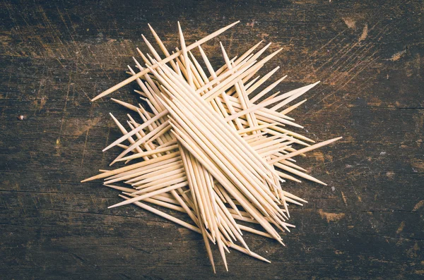 Many toothpicks tightly piled together facing different directions on dark wooden surface — Stock Image Many toothpicks tightly piled together facing different directions on dark wooden surface Stock Picture