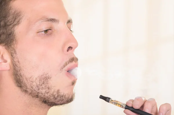 Closeup headshot of man smoking on electronic cigarette from profile angle — 图库照片
