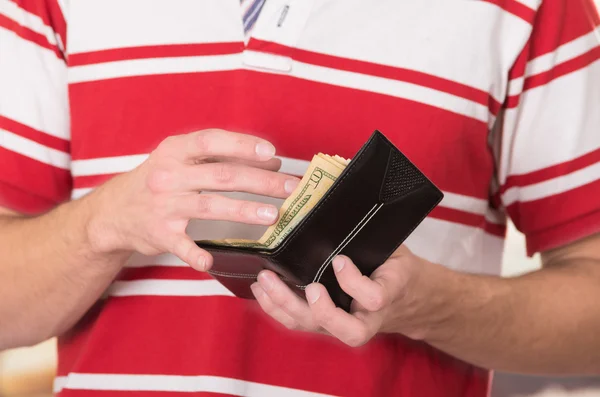 Hombre vistiendo camisa de rayas blancas rojas sosteniendo billetera con dinero y tarjetas visibles —  Fotos de Stock