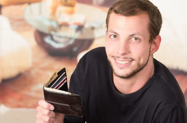 Hispanic male wearing dark sweater looking into camera holding up his wallet revealing its content — Stockfoto