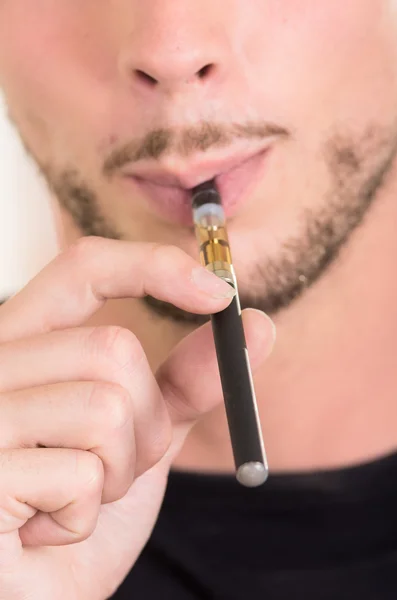 Closeup face of hispanic man with facial hair wearing dark sweater enjoying an electronic cigarette while posing for camera — Stok fotoğraf