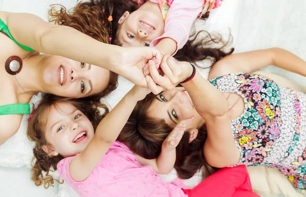 Young adorable hispanic girls and mothers lying down with heads touching, bodies spread out different directions closeup — Stockfoto