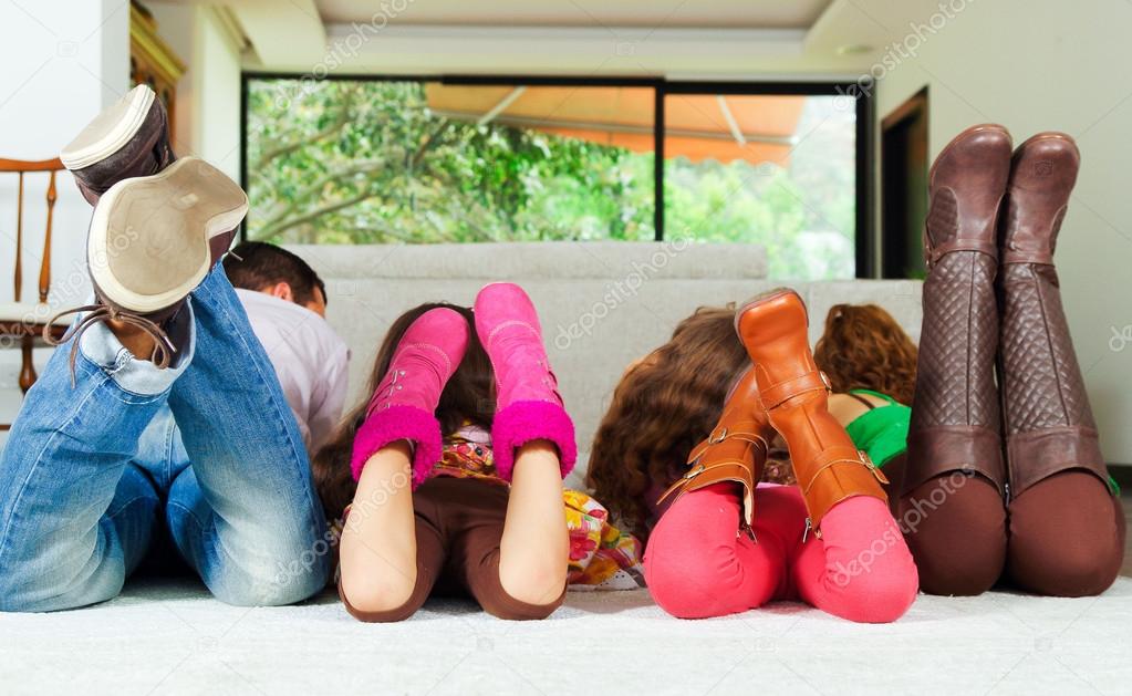 Family of four lying down facing away from camera with feet up in air