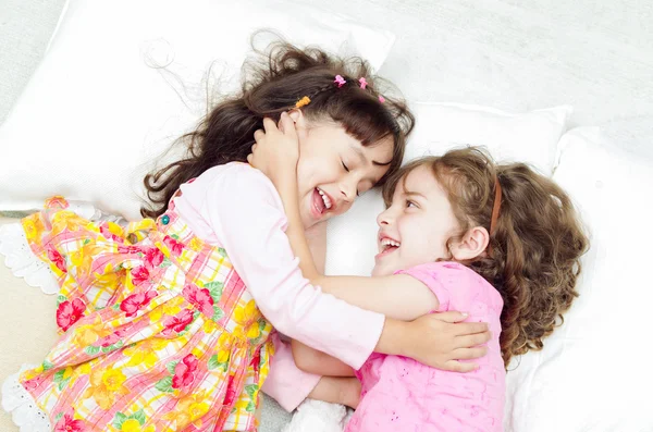 Ung bedårande spansktalande systrar liggande spelar och omfamna varandra glatt medan leende till kameran, skott från ovan vinkel — Stockfoto