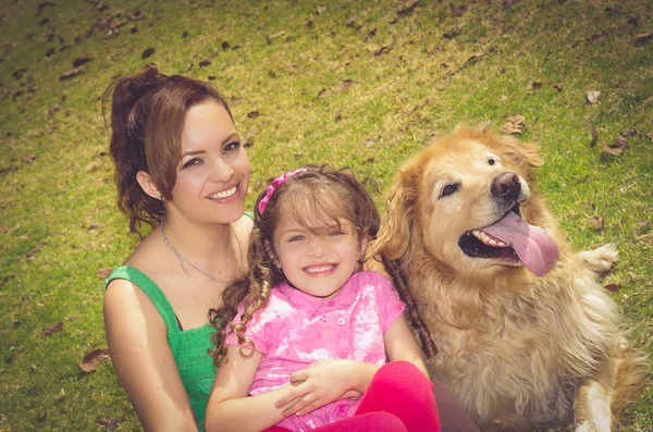 Mãe, filha e cão golden retriever sentado fora no parque ambiente rindo, desfrutando — Fotografia de Stock