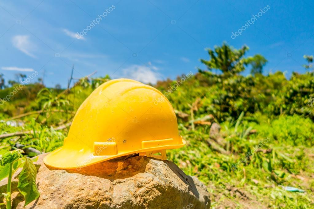 Yellow hard hat with a coffee plantation farm in the background