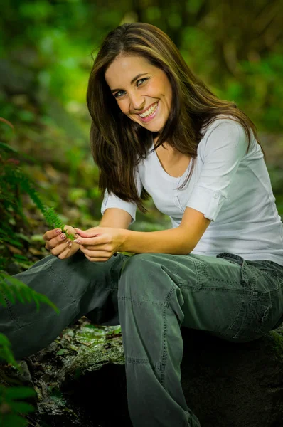 Happy young woman holding a leaf in the forest — 图库照片