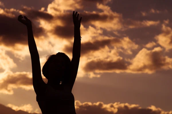 Ragazza adolescente in posa con il tramonto dietro le nuvole in background creando colori spettacolari, concetto di silhouette — Foto Stock