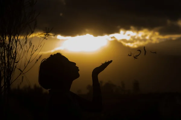 Adolescente posant avec coucher de soleil derrière les nuages en arrière-plan créant des couleurs spectaculaires, concept de silhouette — Photo