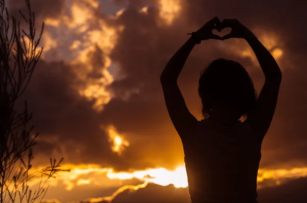 Ragazza adolescente in posa con il tramonto dietro le nuvole in background creando colori spettacolari, concetto di silhouette — Foto Stock